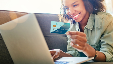 Young lady on sofa ordering online with AFFCU credit card