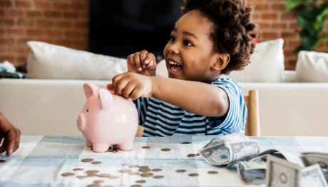 AFFCU Journey Savings Account Young boy smiling outting coins in piggy bank