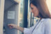 a lady uses an ATM to take money out of her checking account.