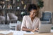 A smiling lady looks at the auto loan refinance rates online on her laptop