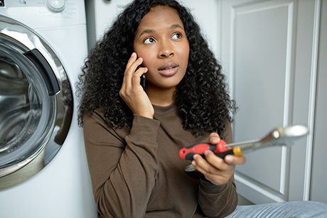 A woman calls a repair person to fix her broken washing machine and pays with a personal loan.