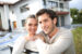 A young couple is standing in front of their home considering home equity options.