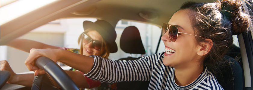 Two young women driving in car laughing