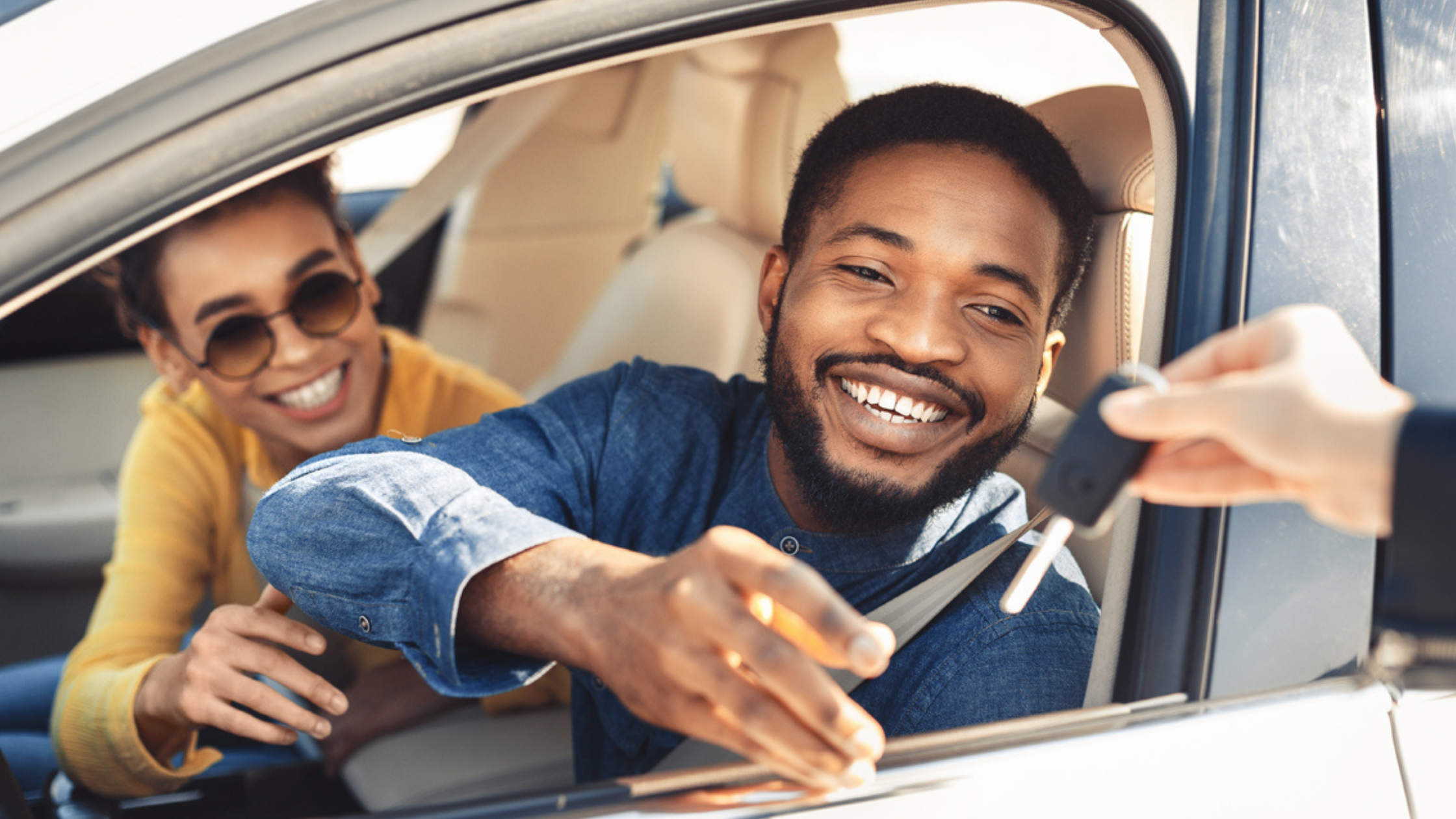 African American Husband and Wife In Vehicle. Reaching out to grab new car keys from dealer