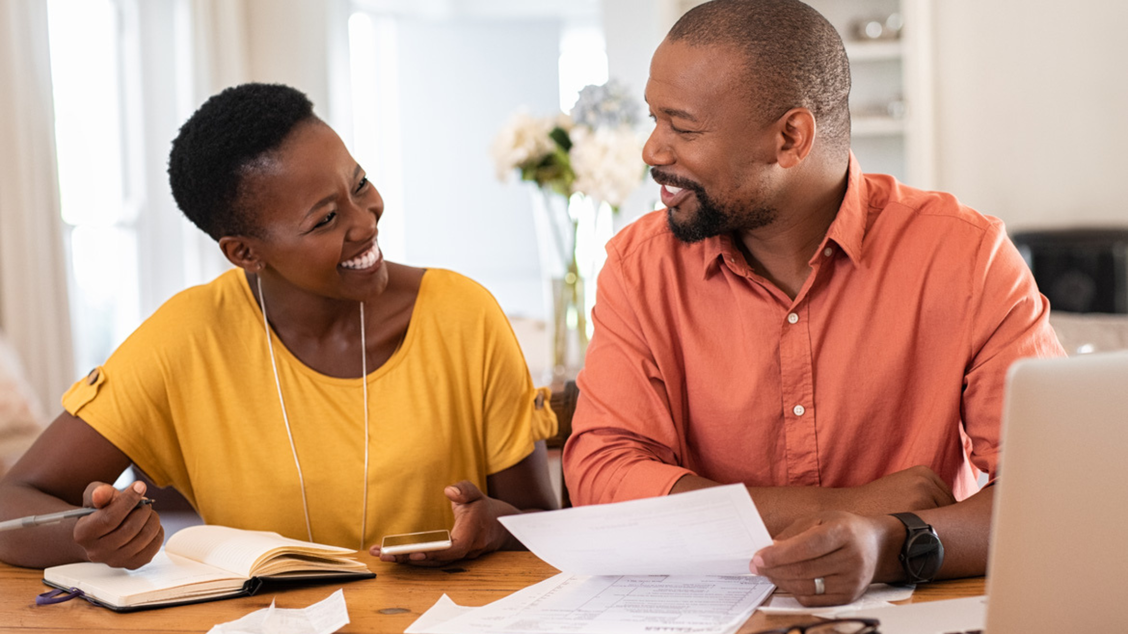 Couple smiling and working together at table to review budget and finances