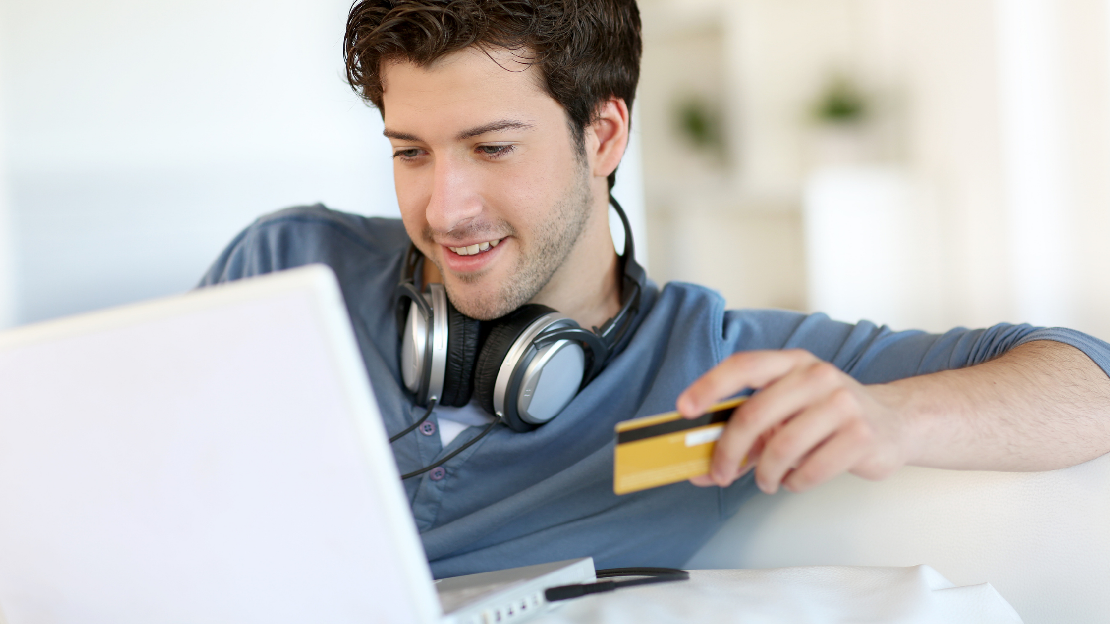 Do's & Don'ts of first credit card blog banner - young man making online purchase with credit card on laptop