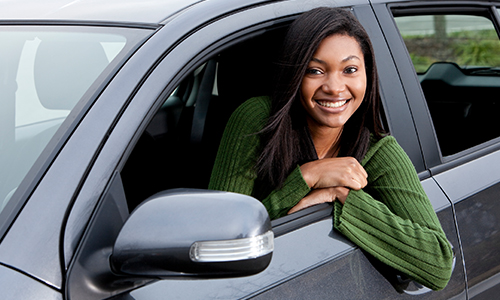 Young girl in car window smiling as a new driver