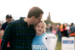 Young girl holding white lantern wearing LLS survivor shirt being kissed on forehead by father