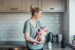 AFFCU Voice Banking - MOther holding baby in kitchen using voice assistant speaker