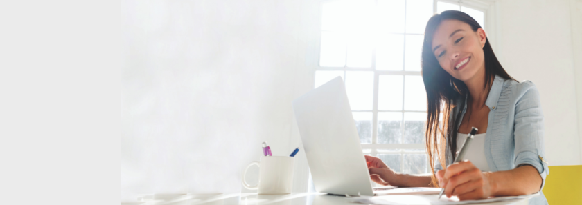 Smiling woman sitting at desk in front of laptop successfully managing her finances