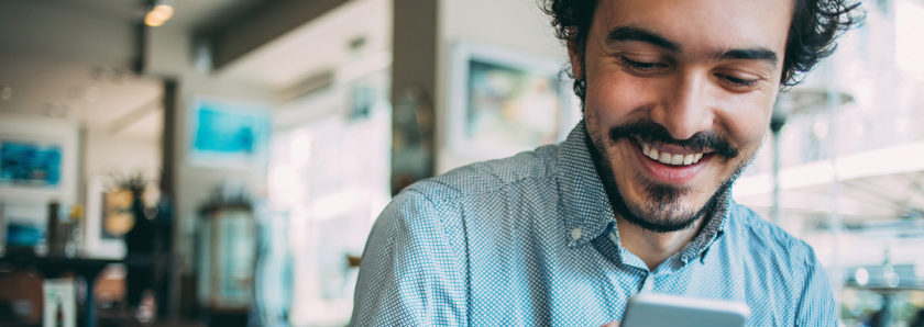 Man sitting in coffee shop looking at mobile phone