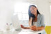 Woman at desk with laptop marking papers