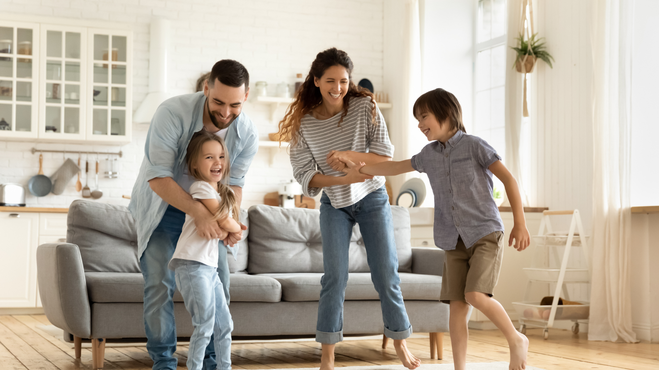 Father, mother, son, and daughter dancing around in family room having fun time