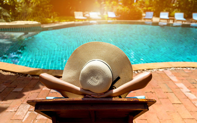 A woman relaxes by the pool on a vacation financed with a personal loan.