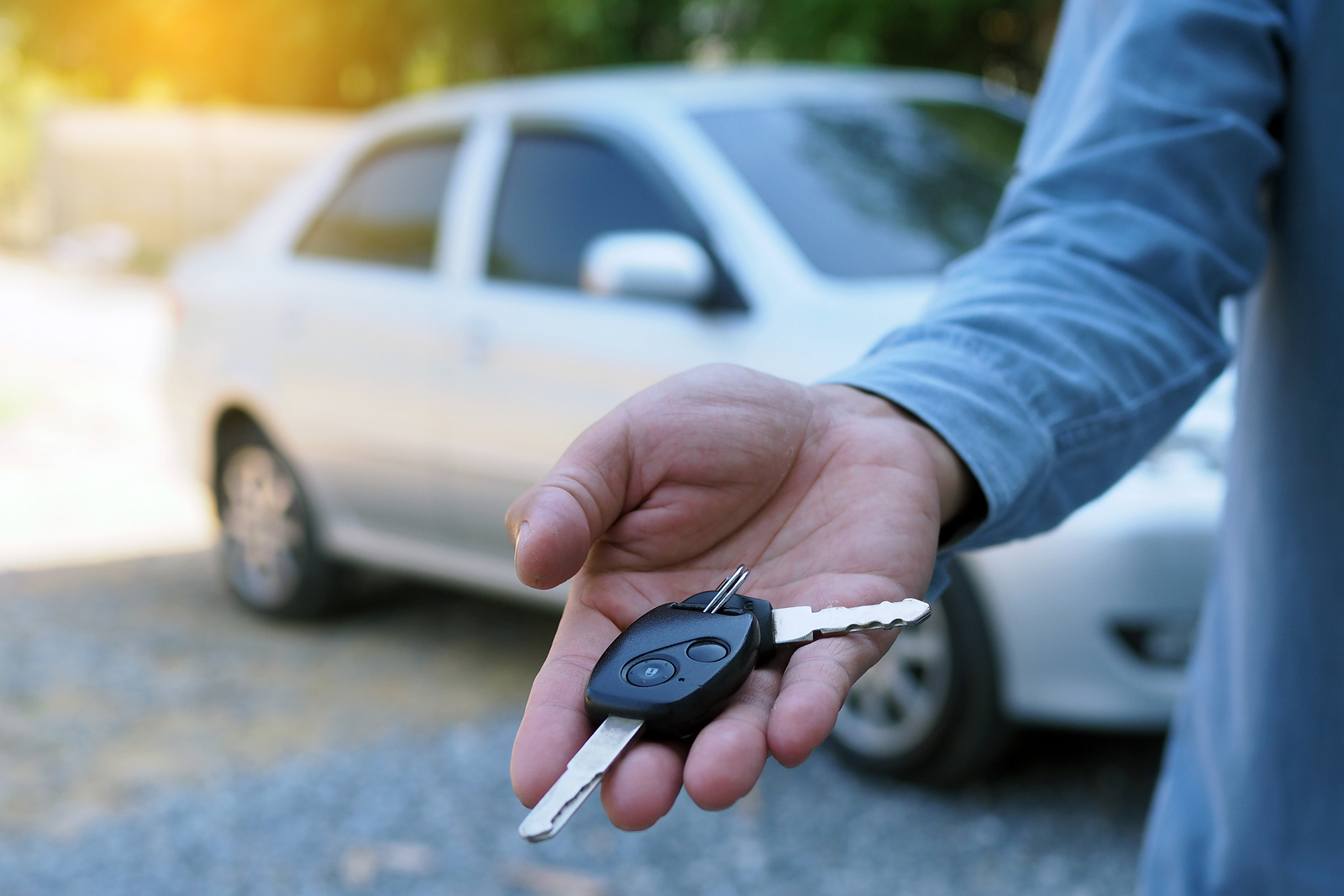 a man standing next to a used car with keys in hand