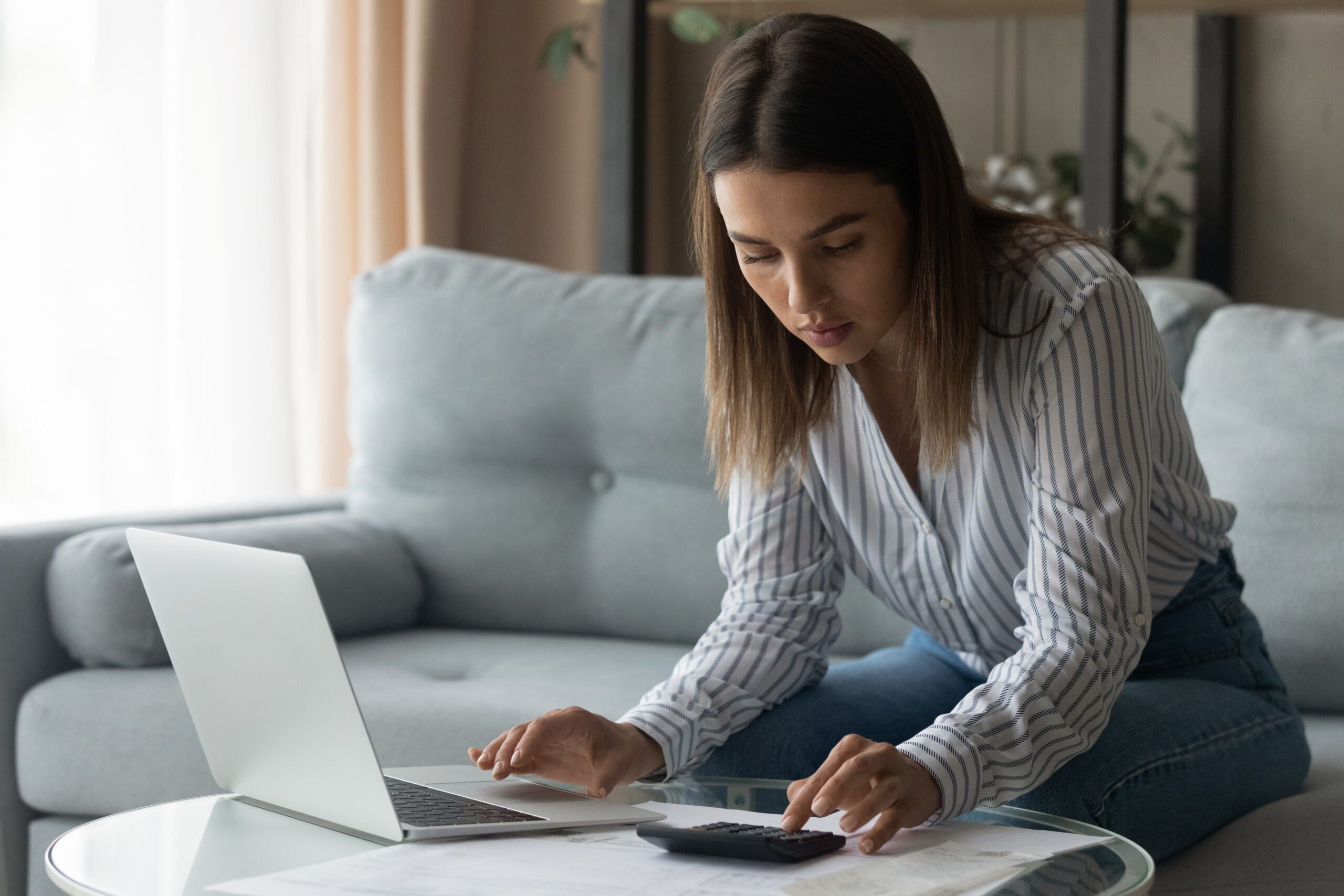 a woman calculates checking account fees to see how much she is spending each month