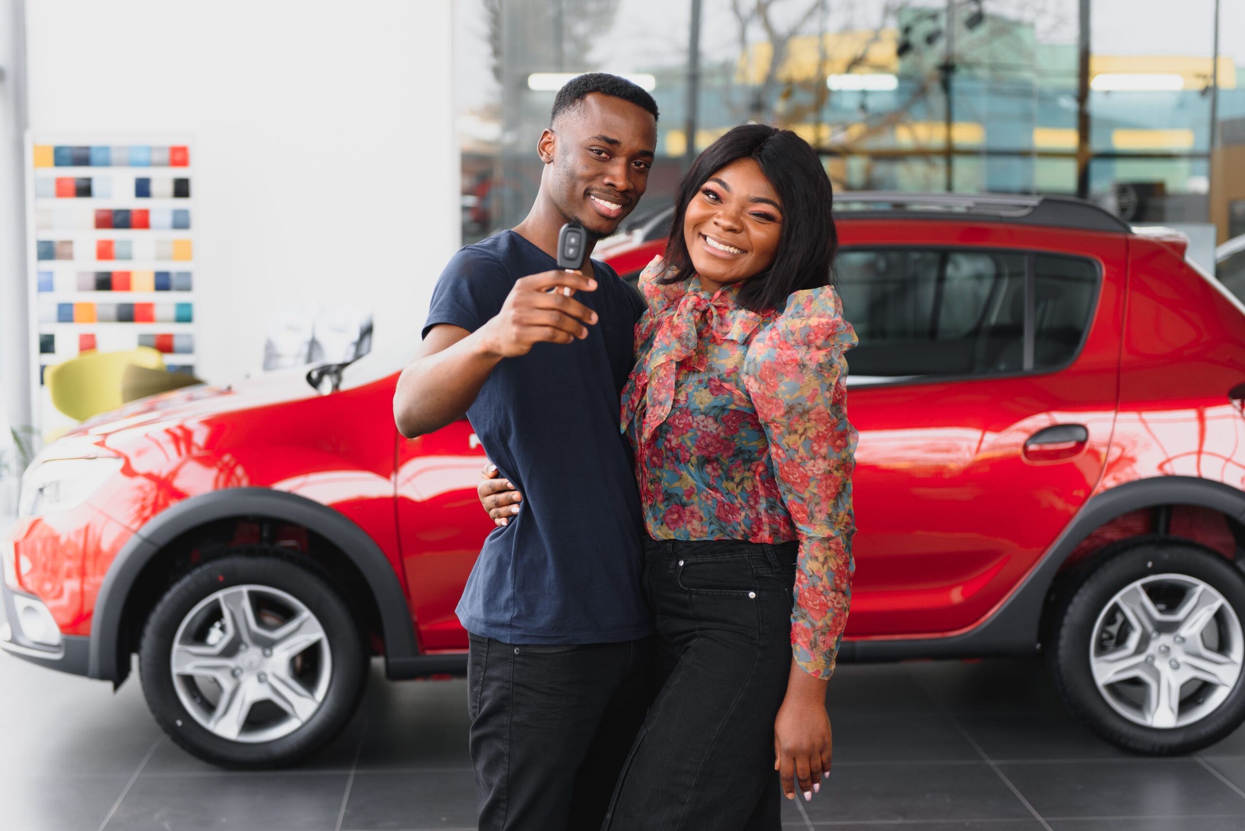 A couple smiles in front of their new car after determining how much car they could afford