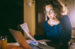 Young lady holding bill looking at laptop