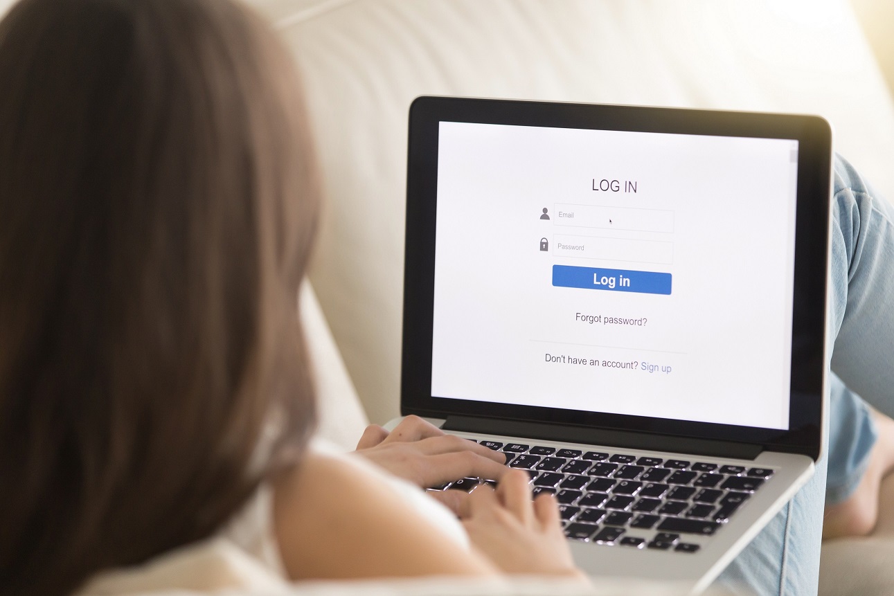 Lady on couch with laptop displaying log in