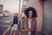 Young lady walking ahead of friends smiling while looking at mobile phone