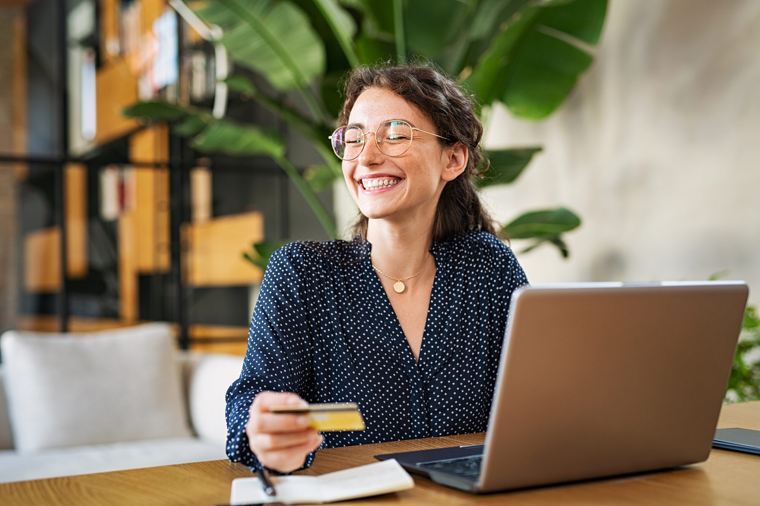 A woman smiles after paying bills online with her debit card from her rewards checking account